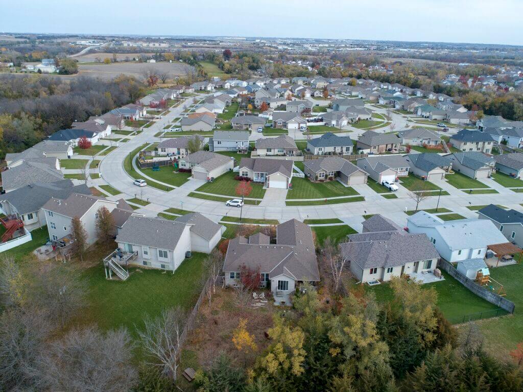 Aerial image of a typical suburban development with homes spaceds tightly and dominated by lawn with hardly a trees or garden bed in sight. These suburban neighborhoods are high maintenance and highly toxic, given the amount of fertilzier and herbicide used to maintain lawn monoculture, as well as the exhaust from fossil-fuel burning mower and blowers. Lawns such as these are not safe places for kids to play.