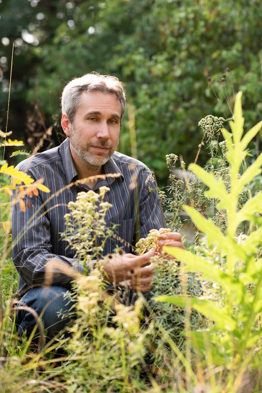 Author and designer Benjamin Vogt kneeling in a prairie garden he created.