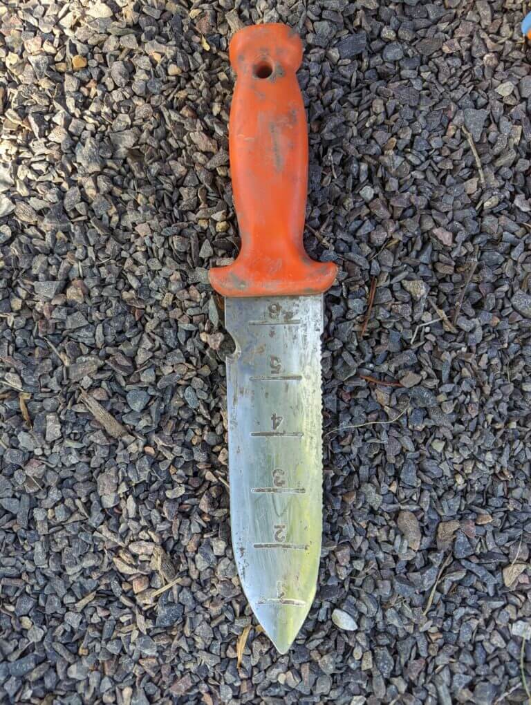 An orange-handled soil knife is a very useful garden tool to have on hand when planting plugs and small plants.