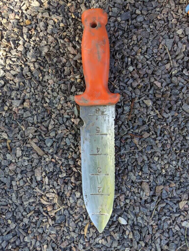 An orange-handled soil knife is a very useful garden tool to have on hand when planting plugs and small plants.